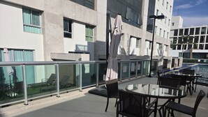 Eine Dachterrasse mit Glasgeländern, Sitzgelegenheiten im Freien und einem Swimmingpool.