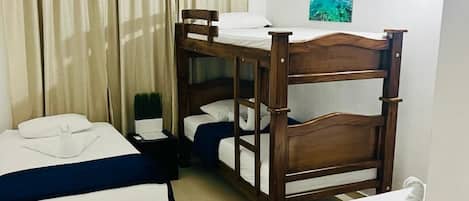 A hotel room with bunk beds, a single bed, an air conditioning unit, a painting on the wall, and a curtain.