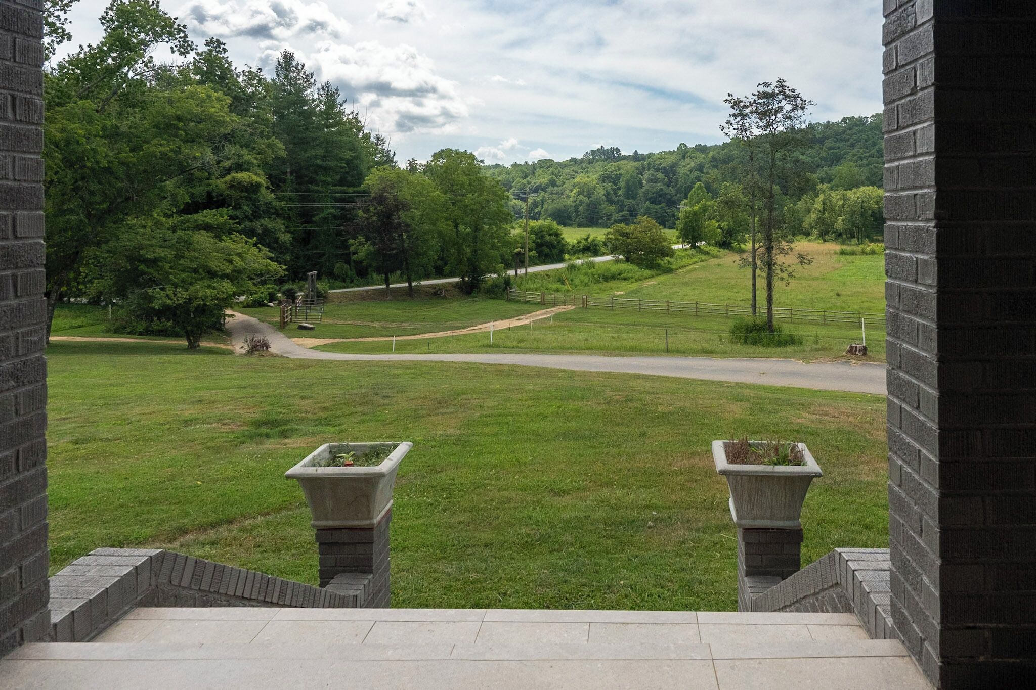 A view from a building with a paved area and two stone planters.