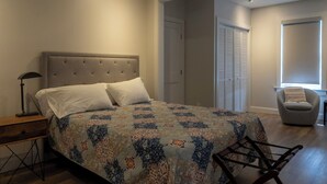 A bedroom with a bed, a nightstand, a chair, and a window.