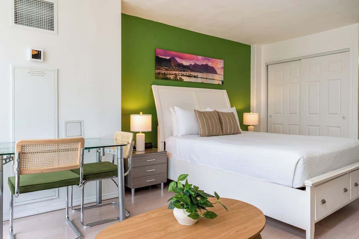 Een slaapkamer met een bed, nachtkastjes, een stoel, een lamp en een plant.