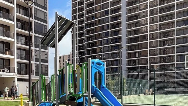 Ein Spielplatz mit Rutschen und Klettergeräten, umgeben von Hochhäusern.
