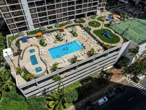 Ein Hotel mit Pool auf dem Dach, Außenbereich zum Sitzen und einem Tennisplatz.