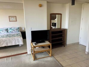 Ein Zimmer mit einem Bett, einem Fernseher auf einem Schrank, einem Spiegel und einem Kleiderschrank.