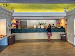 A reception desk with a sign reading 'AQUA Palms,' a wooden floor, and a yellow ceiling. - Renovated Studio, Steps to Waikiki Beach, Parking (Honolulu)