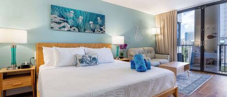 A hotel room with a large bed, a seating area, a balcony with a view, and a wall painting.