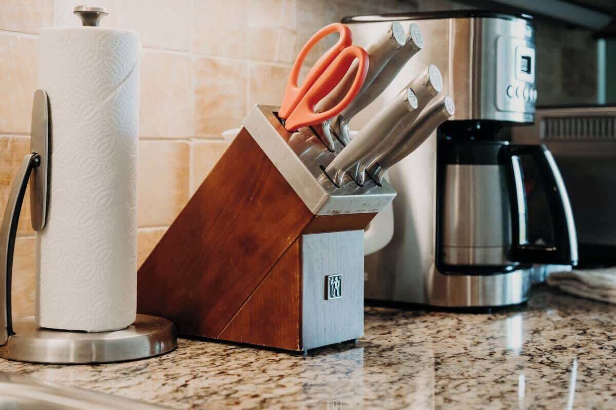 A kitchen counter with a paper towel holder, a knife block, and a coffee maker.