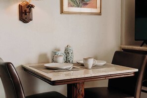 A dining table with plates, cups, and a pitcher, surrounded by chairs. - Central Waikiki Studio, City View, Pool, 2 Queens (Honolulu)