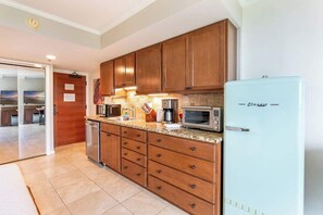 A kitchen with wooden cabinets, a light blue refrigerator, a microwave, and a toaster. - Central Waikiki Studio, City View, Pool, 2 Queens (Honolulu)
