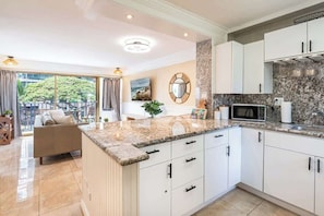 A modern kitchen with white cabinets, granite countertops, and a large island. - Central Waikiki 2 Bedroom, AC, Lanai, Pool, King (Honolulu)