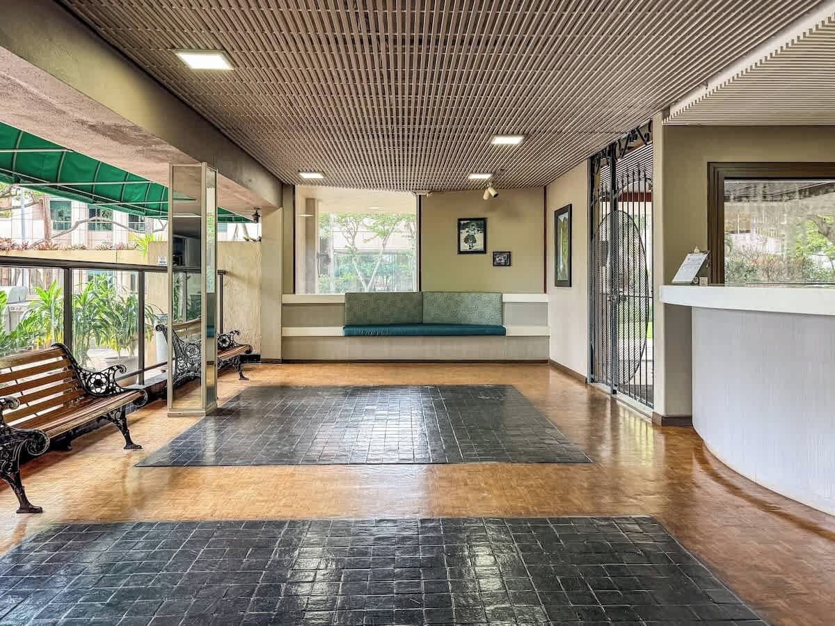 A spacious indoor area with a wooden floor, a bench, and a reception desk.