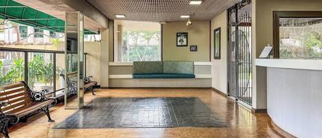 A spacious indoor area with a wooden floor, a bench, and a reception desk.
