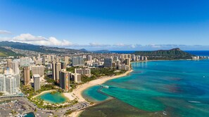 A coastal cityscape with high-rise buildings, a beach, and clear blue waters. - Heart of Waikiki | Walkable, King Bed, Beach Gear. (Honolulu)