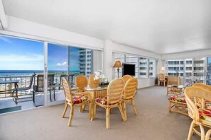 A spacious room with a balcony, wicker furniture, and large windows. - Oceanview Marina Front, Steps to Waikiki Beach (Honolulu)