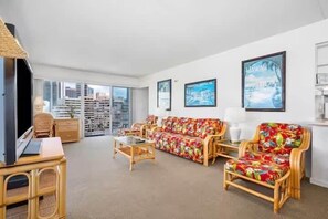 Ein Wohnzimmer mit einer Sofagarnitur, einem Couchtisch, einem Fernseher und einem Bücherregal.