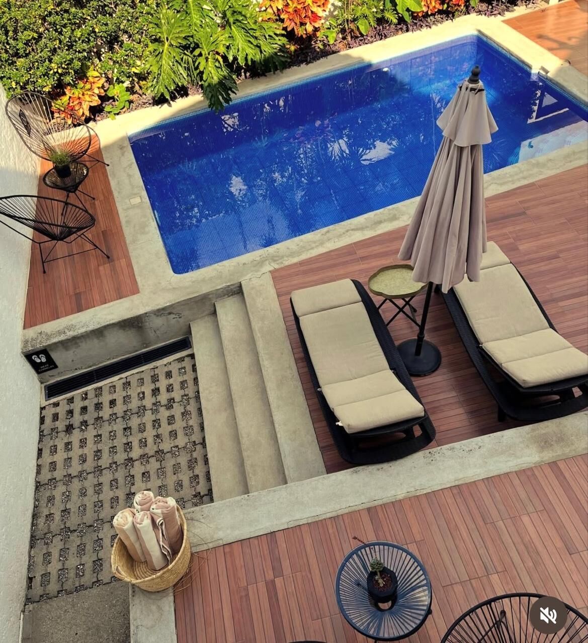 A pool area with lounge chairs, a table, and a chair.
