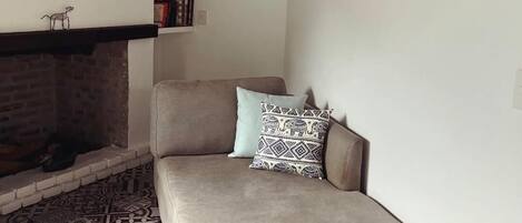 A living room with a sofa, patterned floor, fireplace, and wall-mounted pictures.