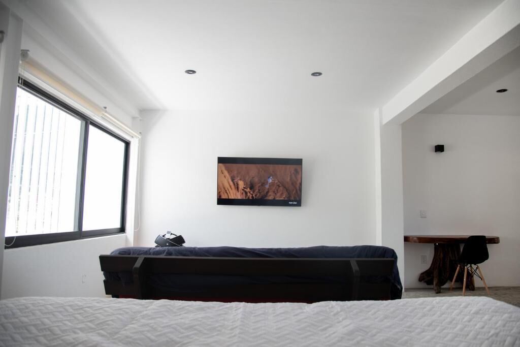 Et moderne hotelværelse med seng, skrivebord, stol og et billede på væggen.