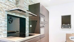 A modern kitchen with a stone backsplash, stainless steel appliances, and a built-in oven. - Appartement Sorelle, 4 pers, piscine, plage à 2 minutes (LECCI)
