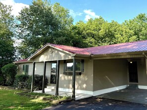 A single-story house with a red roof, beige siding, and a covered porch.