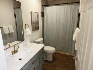 A bathroom with a sink, toilet, and shower curtain.