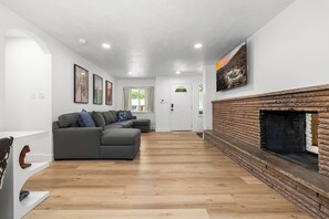 Ein modernes Wohnzimmer mit einem Ecksofa, einem Kamin und gerahmten Kunstwerken an den Wänden.