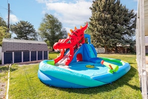 Ein aufblasbarer Spielbereich mit einer Drachenrutsche und einem kleinen Pool.