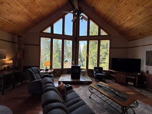 A spacious living room with a high ceiling, large windows, a fireplace, and a television. - Ember Creek 3 Bedroom & Loft, Family Retreat! (Shaver Lake)