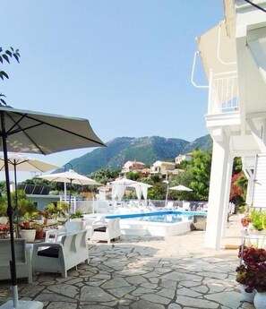 A pool area with lounge chairs, umbrellas, and a view of mountains.