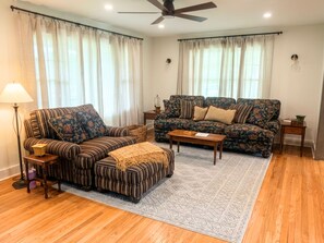 A living room with a sofa, ottoman, coffee table, floor lamp, and a ceiling fan. - Peaceful 3BR Country Retreat w/ Fire Pit • 20 Min to Beach (Maysville)
