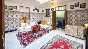 A room with a skylight, patterned walls, a bed with a colorful blanket, and a small table with a lamp. - Stay in the Heart of Marrakech Medina – Private Room, AC & Rooftop Terrace (Marrakech)