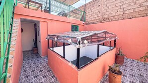 A small, enclosed patio area with a glass table, potted plants, and a brick wall. - Stay in the Heart of Marrakech Medina – Private Room, AC & Rooftop Terrace (Marrakech)