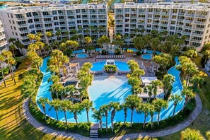 Ein Hotel mit mehreren Schwimmbecken, Palmen und einer zentralen Wasserspiele-Anlage.