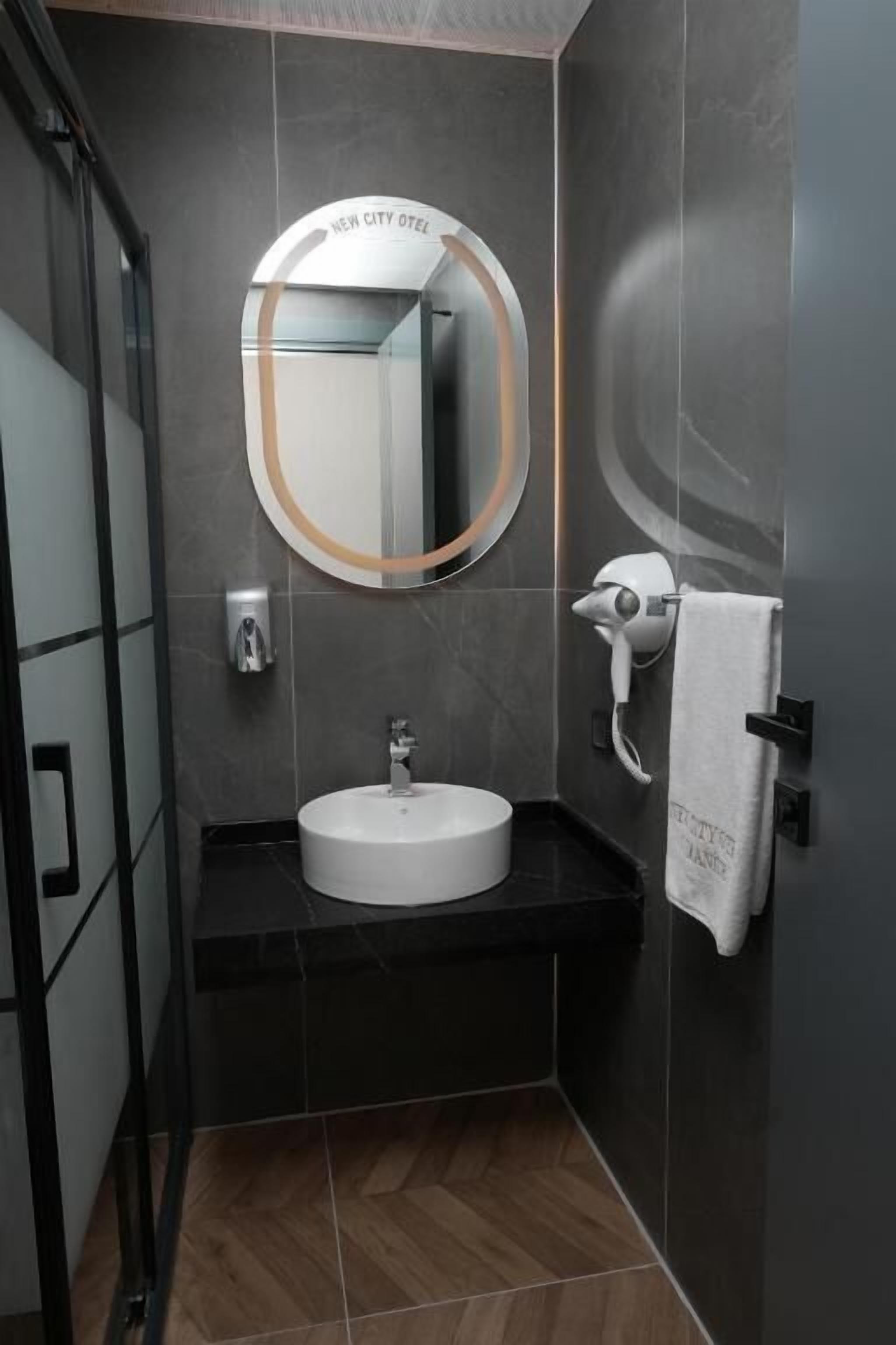 A modern bathroom with a round mirror, a sink, and a towel rack.