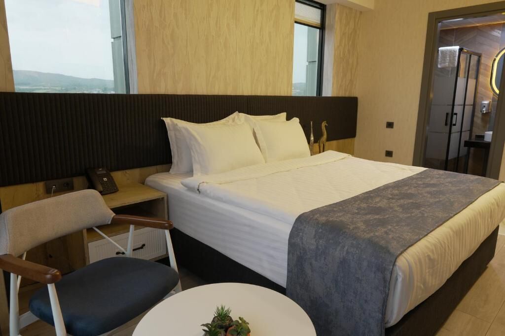 Una habitación de hotel con una cama, un escritorio, una silla y una pequeña mesa con una planta.