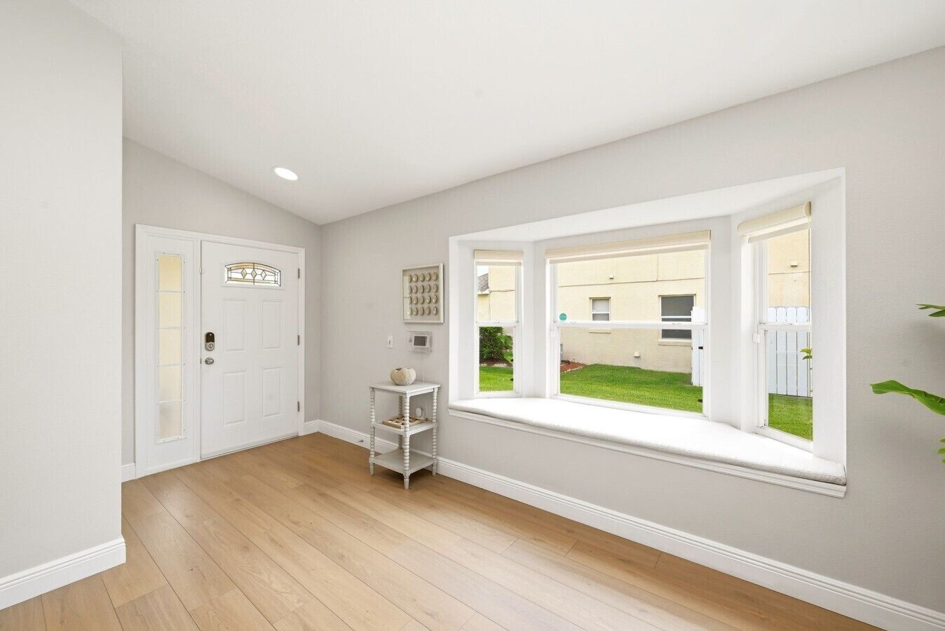 A room with a large window, a door, and a small white table.