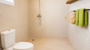 Ein kleines Badezimmer mit Toilette, Dusche und einem Korb mit Handtüchern.