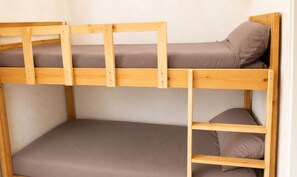 Ein Stockbett mit zwei Ebenen, Holzrahmen und brauner Bettwäsche.