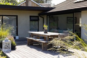 A wooden deck with a table and chairs, potted plants, and a lantern. - Scandi-style Birdham Retreat With Hot Tub Garden (Chichester)