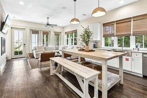 Eine moderne Küche mit Essbereich, Holzboden und großen Fenstern mit Jalousien.