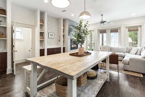 Eine moderne Küche mit Holztisch, Einbauschränken und Deckenventilator.