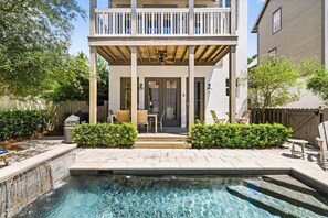 Ein zweistöckiges Haus mit einer überdachten Terrasse, einem Swimmingpool und einem umzäunten Garten.