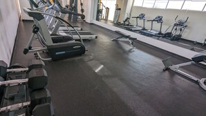 Ein Fitnessstudio mit Laufbändern, Krafttrainingsgeräten und Kurzhanteln.