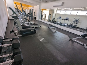 Un gimnasio con cintas de correr, máquinas de pesas y mancuernas.