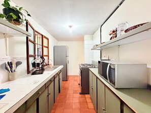 Eine Küche mit Kühlschrank, Herd, Mikrowelle und Schränken.