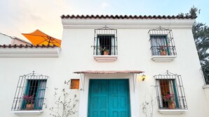 A two-story building with a turquoise door, potted plants, and a balcony with metal railings. - Casa Fernando in Antigua Guatemala (Antigua Guatemala)
