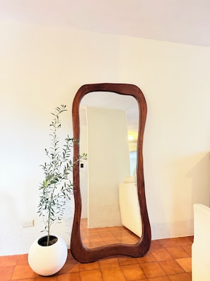 Ein Spiegel mit Holzrahmen, ein Blumentopf und eine weiße Wand.