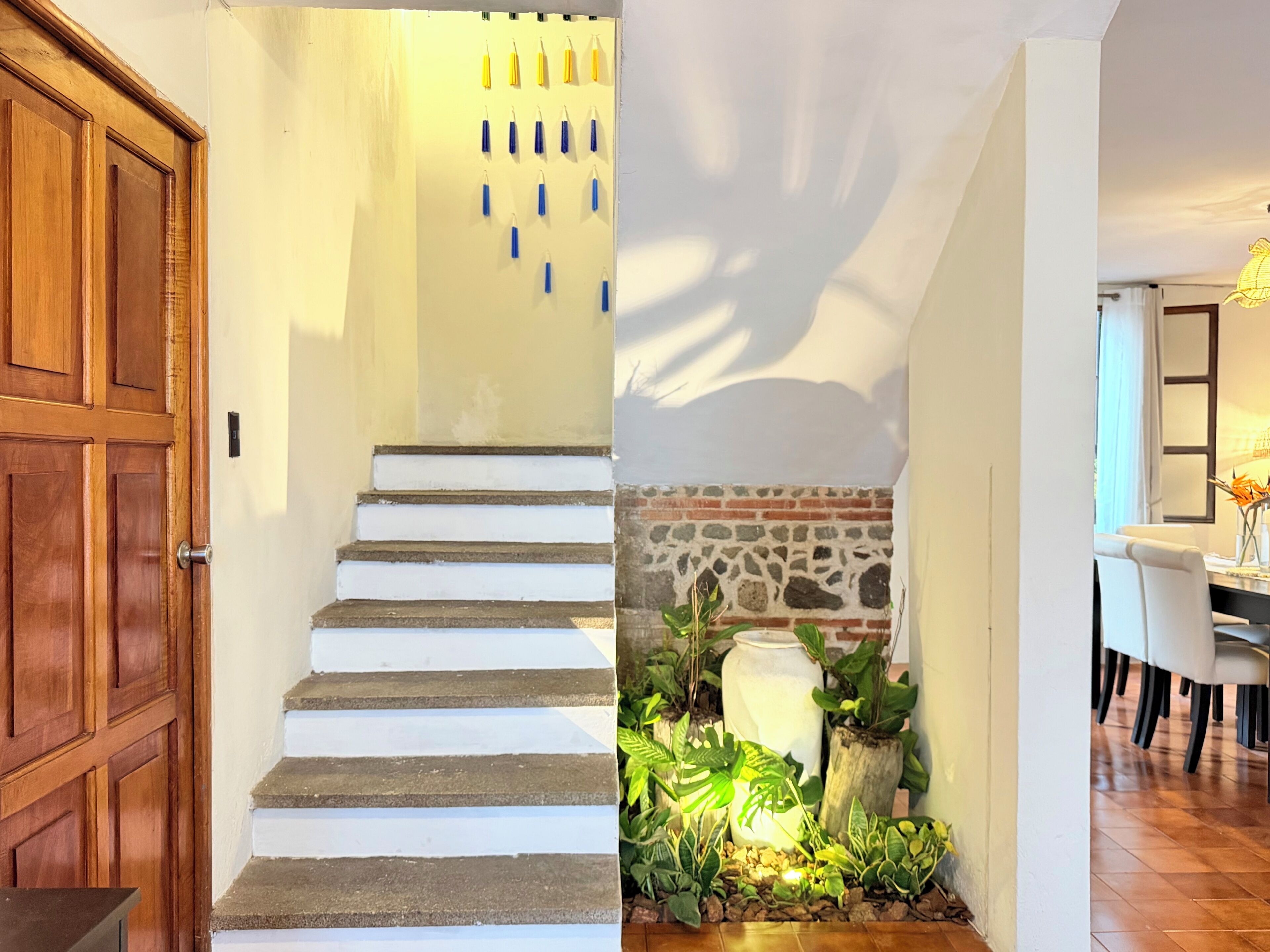 A staircase with white steps, a wooden door, and a stone wall.
