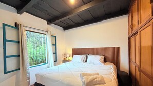 A bedroom with a bed, a nightstand, a window with curtains, and a wooden ceiling. - Casa Fernando in Antigua Guatemala (Antigua Guatemala)