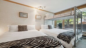 Ein Hotelzimmer mit zwei Betten, Zebra-Muster-Decken, einem Schlafstapelbett und Blick ins Freie.